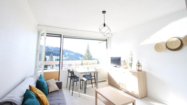 A bright, modern living room with a sofa, chairs, a dining table, and a large window offering a mountain view. - 150m from ski slopes, 2nd floor, balcony, tv, 30m², Chamrousse (Chamrousse)