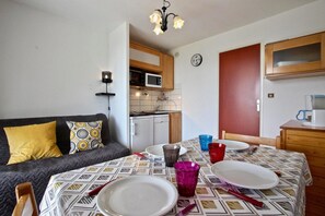 Cozy living space with a kitchenette, sofa, dining table, and microwave.