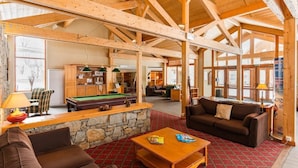A spacious room with a pool table, a sofa, and a wooden ceiling.