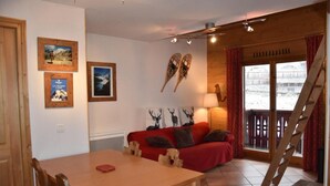 Una habitación acogedora con una mesa de madera, un sofá rojo y una escalera que lleva a un balcón.