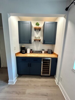 A compact kitchen with dark blue cabinets, a wooden countertop, and a small bar area. - Modern Chic 4-Bedroom Home with Wood Stove Fireplace (Flagstaff)