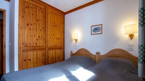 Une chambre avec deux lits, des têtes de lit en bois et des lampes fixées au mur.