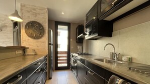 Una cocina moderna con armarios oscuros, electrodomésticos de acero inoxidable y un gran reloj de pared.