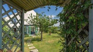 Une pergola en bois avec un chemin de pierre menant à une maison.