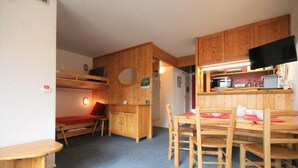 A compact room with bunk beds, a small kitchenette, and a dining area with wooden furniture. - 50m from resort center, 2nd floor, view valley, balcony, tv, 40m², Les Arcs (Les Arcs)