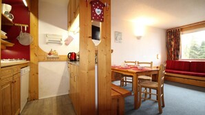 A cozy kitchen with wooden cabinets, a red wall, and a dining area with a wooden table and chairs. - 50m from resort center, 2nd floor, view valley, balcony, tv, 40m², Les Arcs (Les Arcs)