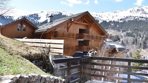 Una cabaña de madera con balcón, con montañas al fondo.