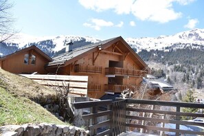 A wooden chalet with a balcony, set against a mountainous backdrop. - 350m from resort center, Ground floor, terrace, tv, 65m², Méribel (Méribel - Les Allues)