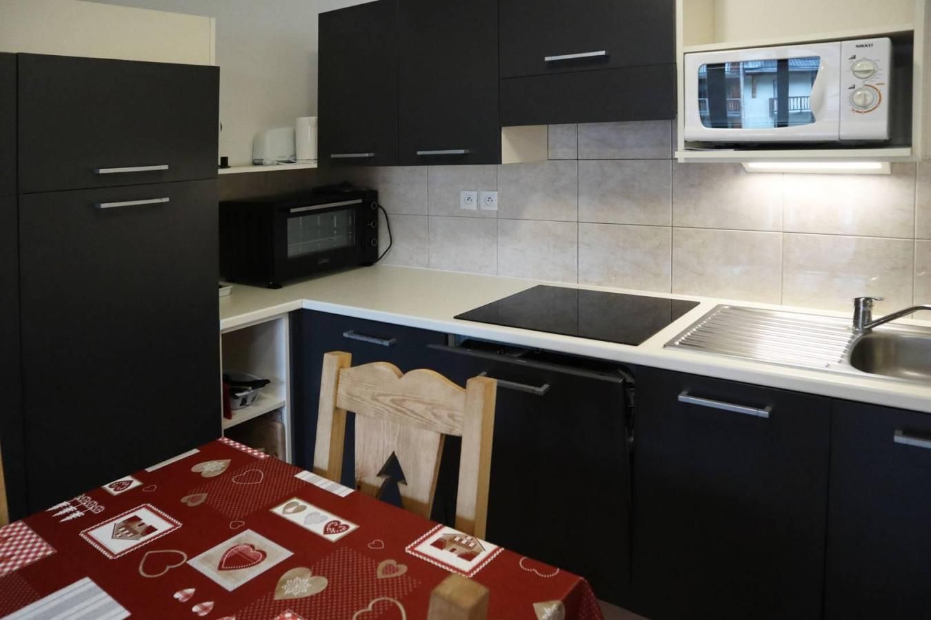 A compact kitchenette with a microwave, stove, and sink.