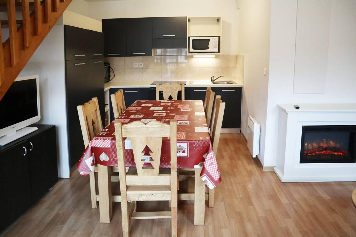 Ein Essbereich mit einem Tisch für vier Personen, Holzstühle, einer Mikrowelle über dem Spülbecken und einem Kamin.