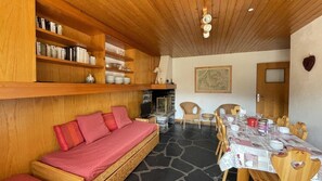 A cozy room with a wooden sofa, a dining table set for four, and a fireplace. - 250m from shops, Ground floor, fireplace or stove, tv, ski locker, 55m², Méribel (Méribel - Les Allues)