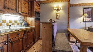Una cocina con armarios de madera, salpicadero de azulejos, un banco y una mesa de comedor.