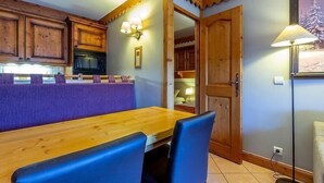 Una cocina acogedora con armarios de madera, encimera morada y comedor con mesa de madera y sillas azules.