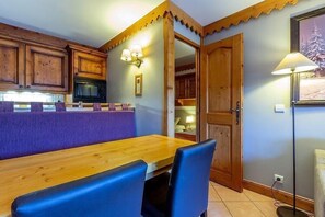 Eine gemütliche Küche mit Holdekor, einer lilafarbenen Arbeitsplatte und einem Essbereich mit Holztisch und blauen Stühlen.
