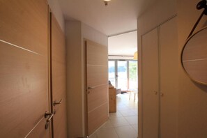 A hallway with wooden doors leading to a room with a view of the outdoors.