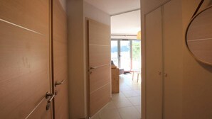 A hallway with wooden doors leading to a room with a view of the outdoors.