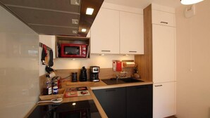 A compact kitchen with a microwave, coffee maker, and sink.