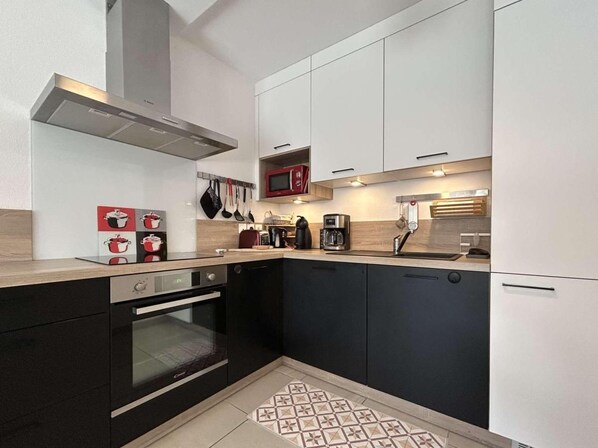 A compact kitchen with a built-in oven, a microwave, and a coffee maker.