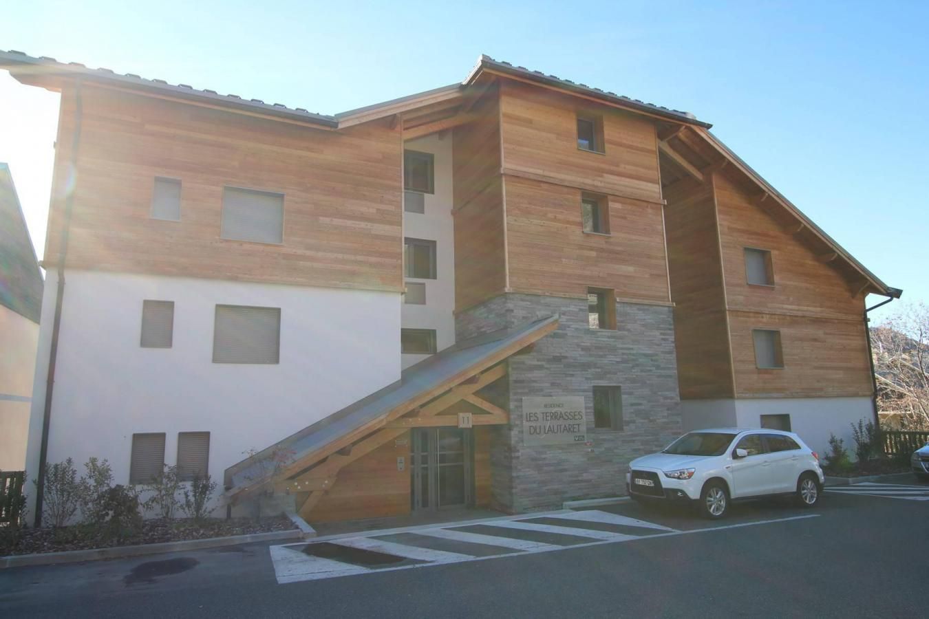 Un bâtiment moderne à deux étages, doté d’une façade en bois et d’un socle en pierre.