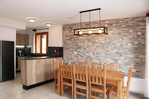 Una cocina moderna con protector contra salpicaduras de piedra, mesa de comedor de madera e isla integrada.
