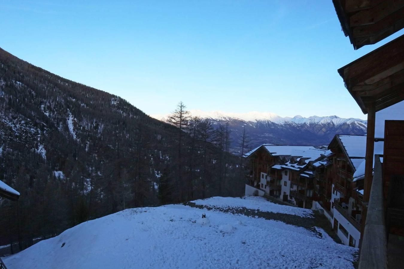A snow-covered mountain landscape with wooden buildings and a clear sky.