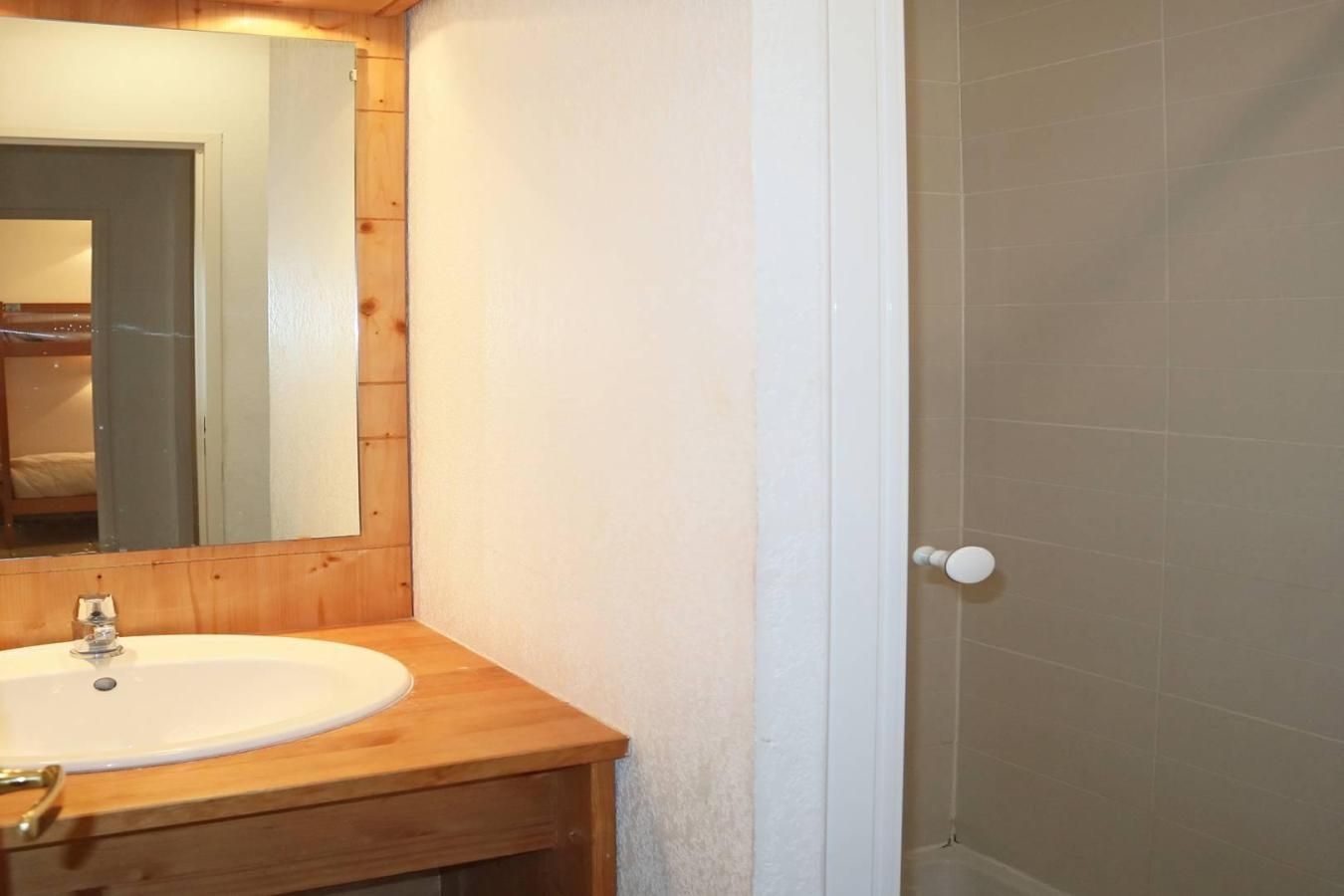 Ein Badezimmer mit einem Holzbidet, einem weißen Waschbecken und einem Spiegel.