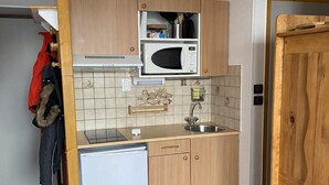 A compact kitchen with wooden cabinets, a microwave, a sink, and a small refrigerator. - 100m from ski slopes, 1st floor, view mountain, balcony, tv, ski locker, 20m², Montalbert (Aime)