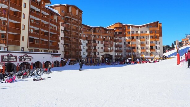 A ski resort with multi-story buildings, ski lifts, and a snow-covered slope.