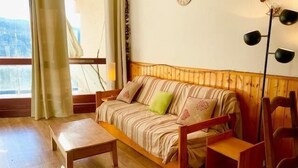 A cozy room with a wooden sofa, a small wooden table, and a floor lamp. - 7th floor, balcony, parking, tv, 63m², Villard de Lans (Villard-de-Lans)