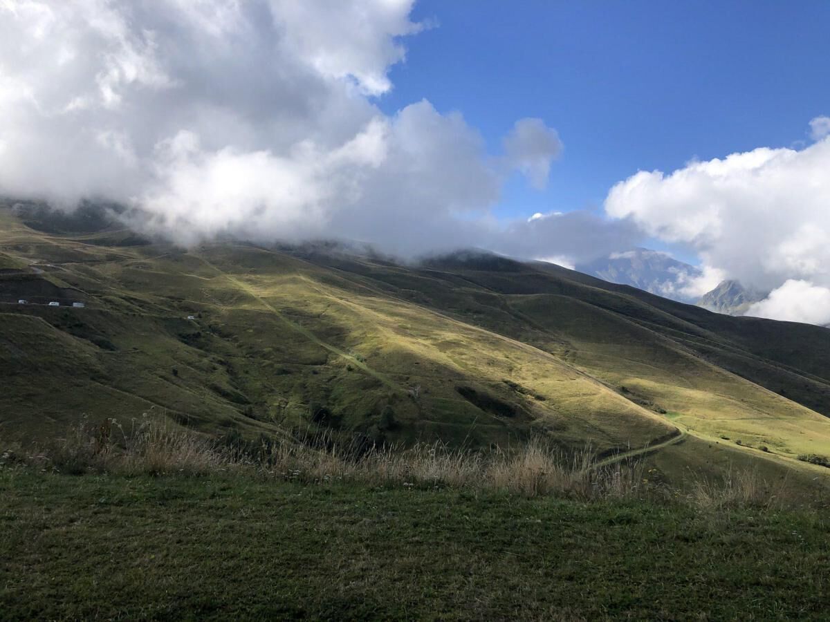 Un paysage vallonné, avec un ciel dégagé et quelques nuages.