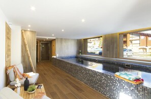 Un bagno moderno con una grande vasca, pavimento in legno e vista esterna.
