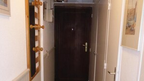 A narrow hallway with wooden flooring, a dark door at the end, and a wooden coat rack on the left wall. - 2nd floor, view mountain, parking, tv, ski locker, 26m², Combloux (Combloux)