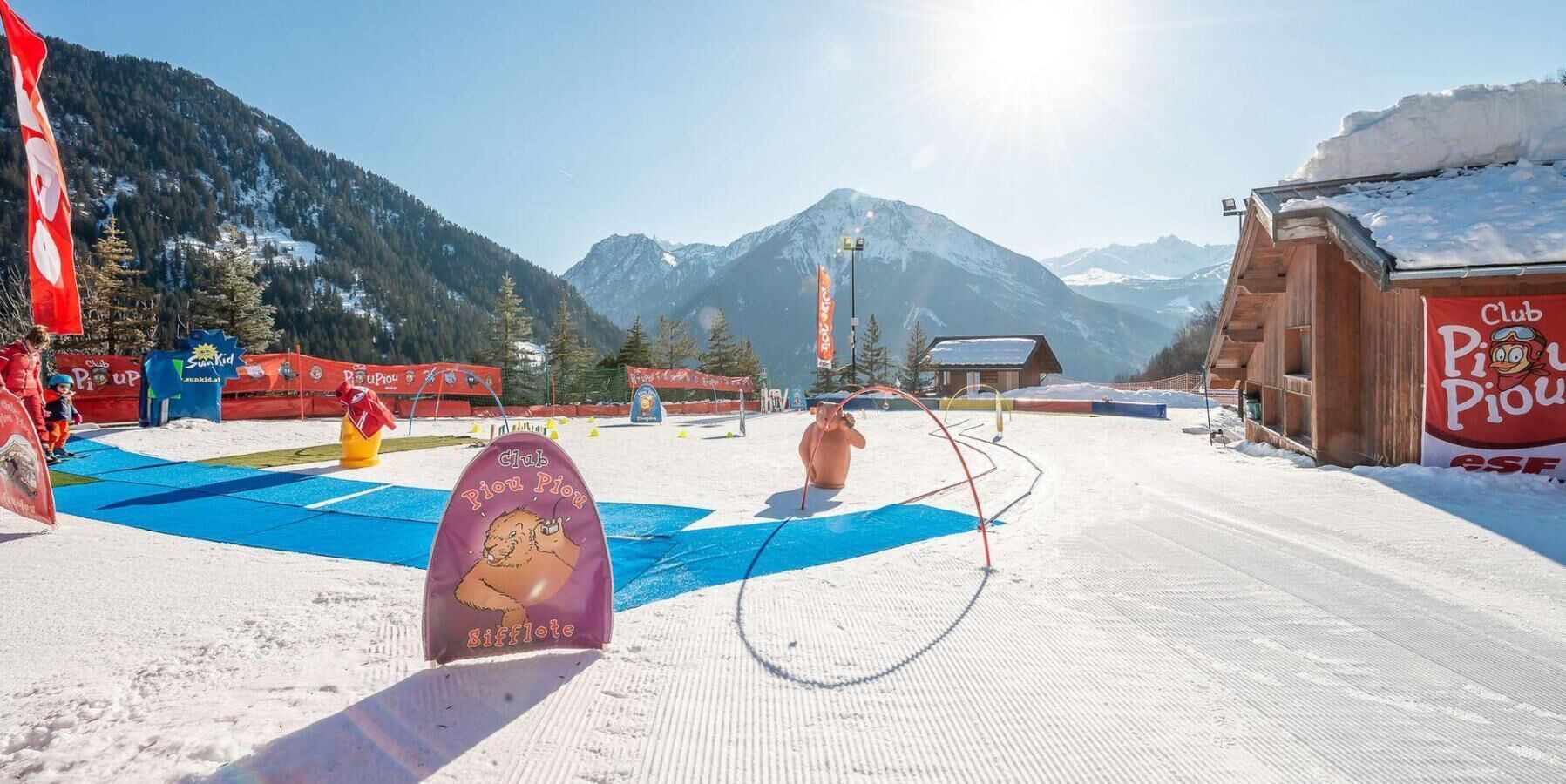 A snowy ski resort with a Club Piu Piu sign, ski lifts, and a mountain backdrop.