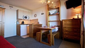 Una cocina compacta con microondas, lavamanos y mesa de madera.