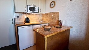 Una cocina compacta con microondas, cafetera y lavabo.