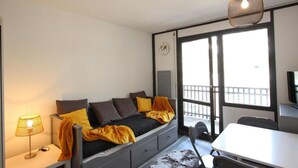 A compact room with a bed, a desk, and a large window. - 300m from ski slopes, 7th floor, balcony, tv, 19m², Chamrousse (Chamrousse)