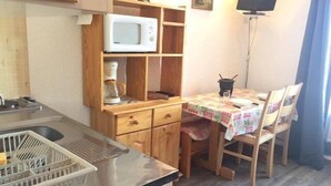 A compact kitchen with a microwave, coffee maker, and a small table with chairs. - 50m from ski slopes, 1st floor, view mountain, balcony, tv, ski locker, 20m², Risoul (Risoul)