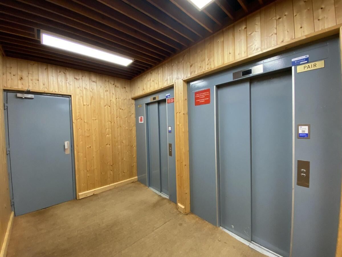 A hallway with wooden walls and blue elevator doors, one marked "PAIR".