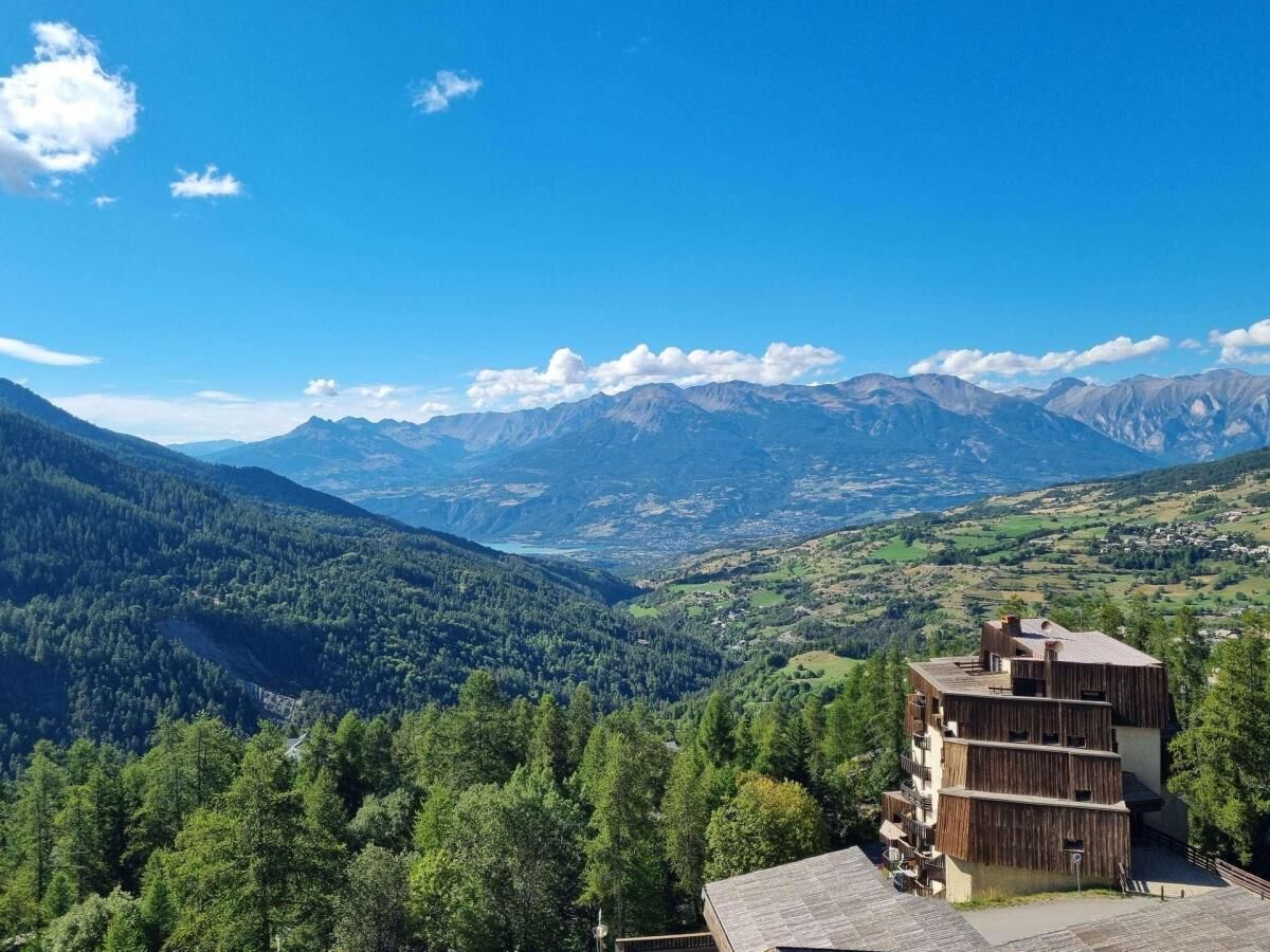 A mountain view with a wooden building in the foreground.