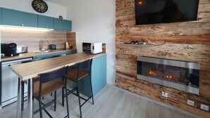 A modern kitchen with a wooden accent wall, a built-in microwave, and a fireplace.