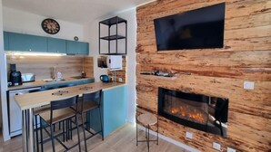 A modern kitchen with a central island, a built-in TV, and a fireplace.