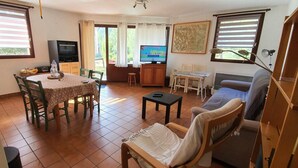 A living room with a dining table, chairs, a sofa, a TV, and a painting on the wall. - Ground floor, terrace, parking, tv, ski locker, 65m², Serre Chevalier (La Salle-les-Alpes)