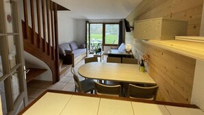 A modern kitchen with a wooden dining table, a built-in oven, and a staircase leading to a balcony.