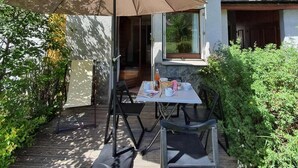 Eine Terrasse im Freien mit Tisch und Stühlen, einem großen Sonnenschirm und einem Holzdeck.