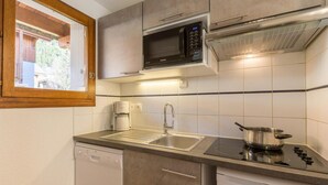A compact kitchen with a built-in microwave, a coffee maker, a sink, and a stove.