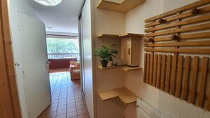 Un couloir avec un lambris en bois, une plante en pot et un lit à l’arrière-plan.
