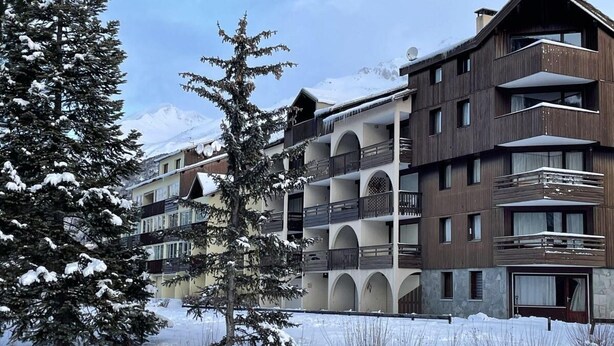 Un hôtel à plusieurs étages, doté de balcons, qui offre une vue sur un paysage enneigé.