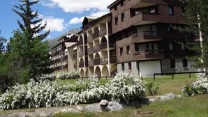 Un hôtel à plusieurs étages doté de balcons, d’une façade en pierre et surplombant un paysage montagneux.