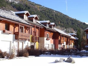 Une rangée de chalets en bois dotés de balcons, se dressant sur fond de montagnes enneigées.