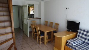 A compact living space with a dining table, chairs, a sofa, a TV, and a staircase. - Chalet, terrace, parking, tv, 62m², Serre Chevalier (La Salle-les-Alpes)
